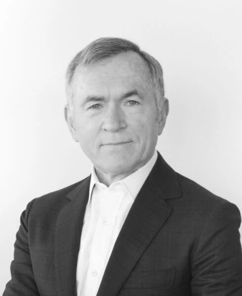 A grayscale portrait of David Puth, a middle-aged man with short, graying hair, wearing a dark suit jacket over a white collared shirt, looking directly at the camera.