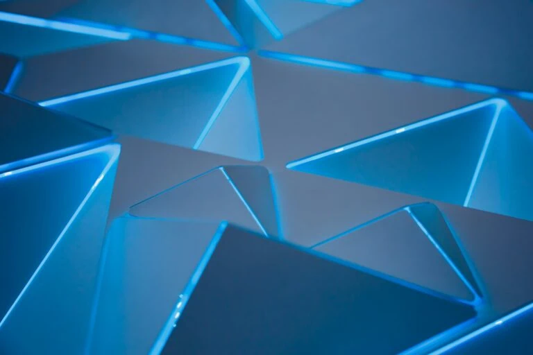 Close-up of a geometric pattern with triangular shapes, illuminated by blue light, creating a modern and futuristic aesthetic that appeals to global investors.