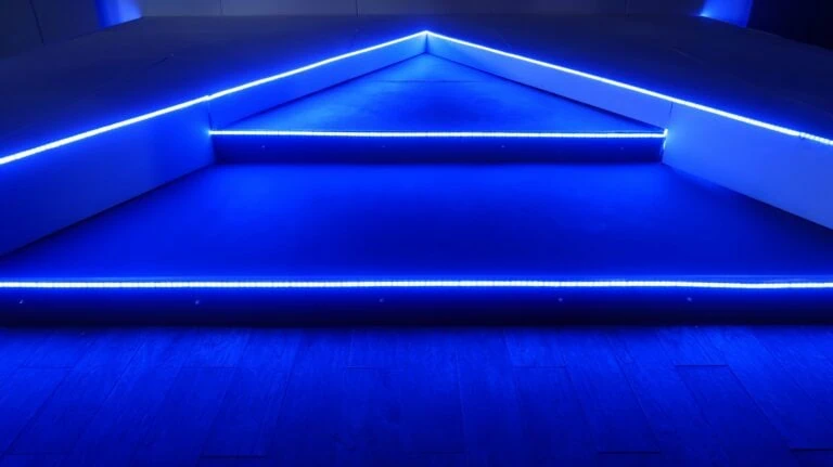 A stage with steps is illuminated with blue LED strip lights, creating a modern and sleek appearance, ideal for immediate deployment at events.