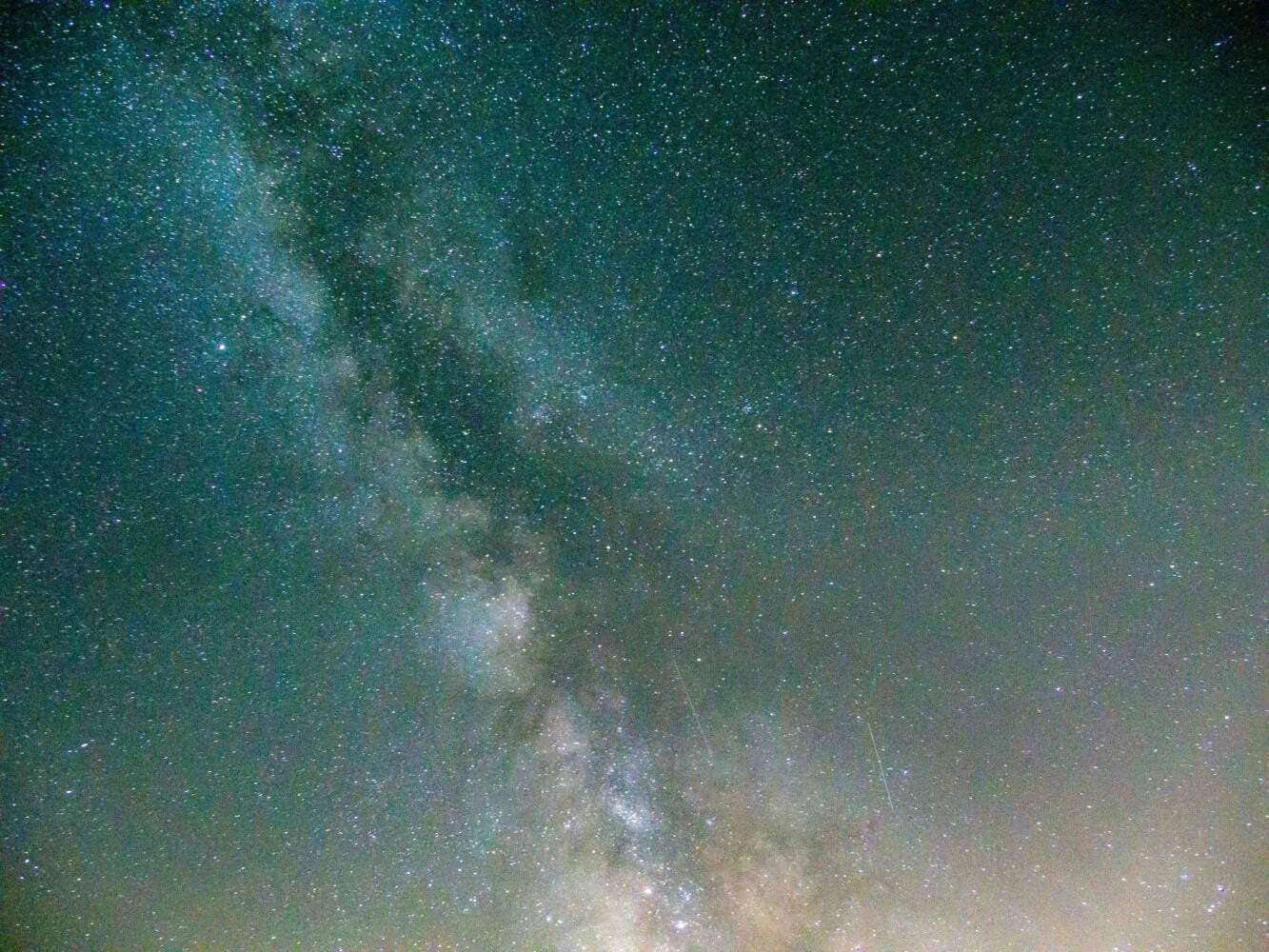 A view of the Milky Way galaxy with dense clusters of stars, set against a greenish-blue night sky, offers golden insights into the mysteries of our universe in 2022.