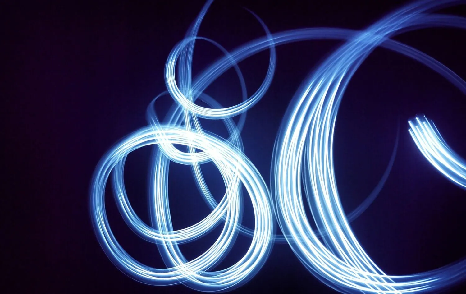 Abstract light painting with multiple overlapping blue circles and arcs on a black background, offering a glimpse into the dynamic energy of emerging markets.