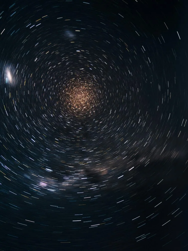 Circular star trails in the night sky create a vortex-like pattern against a dark background, reminiscent of insights from 2021. The lines of light suggest a long-exposure photograph capturing the stars' movement.