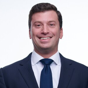 mikedc Michael DiChiara, in a dark suit, white shirt, and blue tie, smiles at the camera against a plain white background.