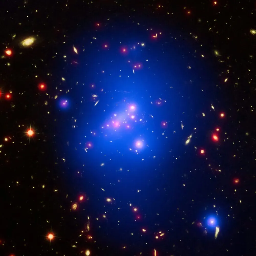 Image showing a galaxy cluster with bright spots of blue, red, and yellow light amidst a dark space background. The blue regions represent X-ray emissions from hot gas in the cluster—a best practice for interpreting cosmic phenomena.