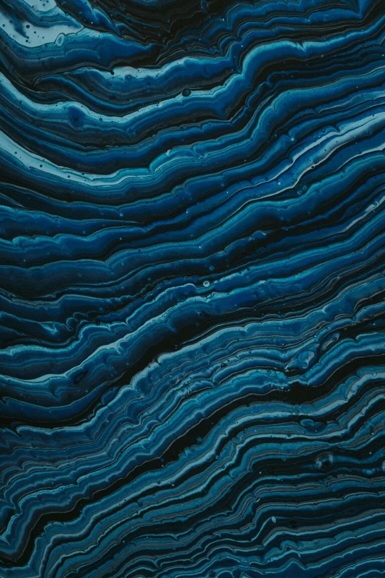 Abstract blue and black wavy pattern with varying shades and textures, reminiscent of geological layers or flowing water, evoking the purity and flow of clean hydrogen.