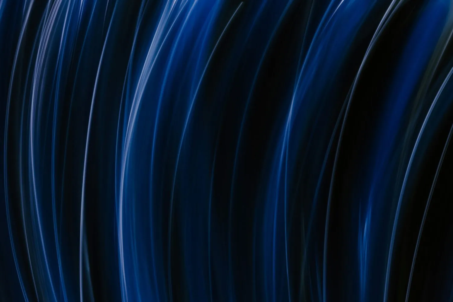 Abstract image featuring fluid, curved streaks of blue light against a dark background, creating a sense of motion and depth. This vibrant scene offers a fresh view that captures the evolving landscape post-COVID-19, blending futuristic aesthetics with contemporary insights from 2022.