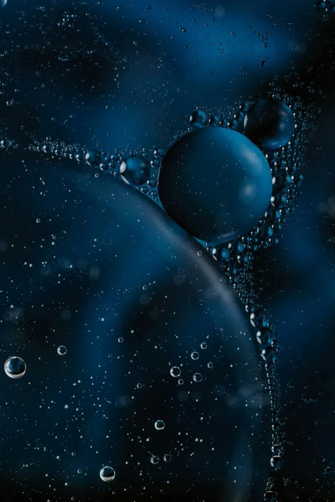 Close-up image of bubbles suspended in a dark blue liquid, creating an abstract and cosmic-like appearance, reminiscent of insights from 2021 on economic growth.