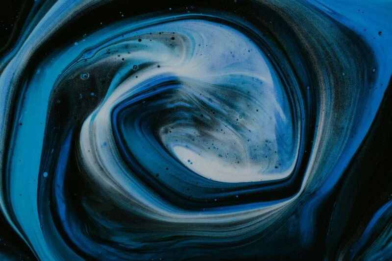 Abstract image featuring swirling shades of blue and black with white accents, resembling a whirlpool or galaxy formation, symbolizing the complex dynamics of an Energy Transition.