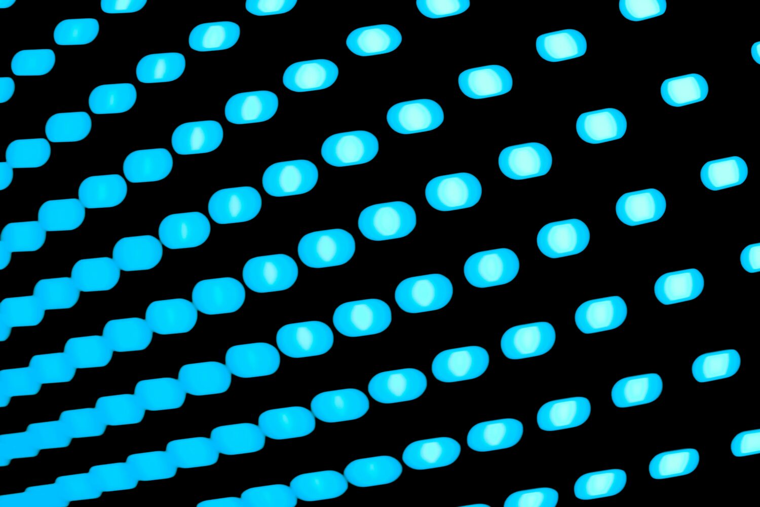 A close-up image of multiple rows of bright blue LED dots arranged diagonally against a black background, offering visual insights as striking as the shifting interest rates in 2021.