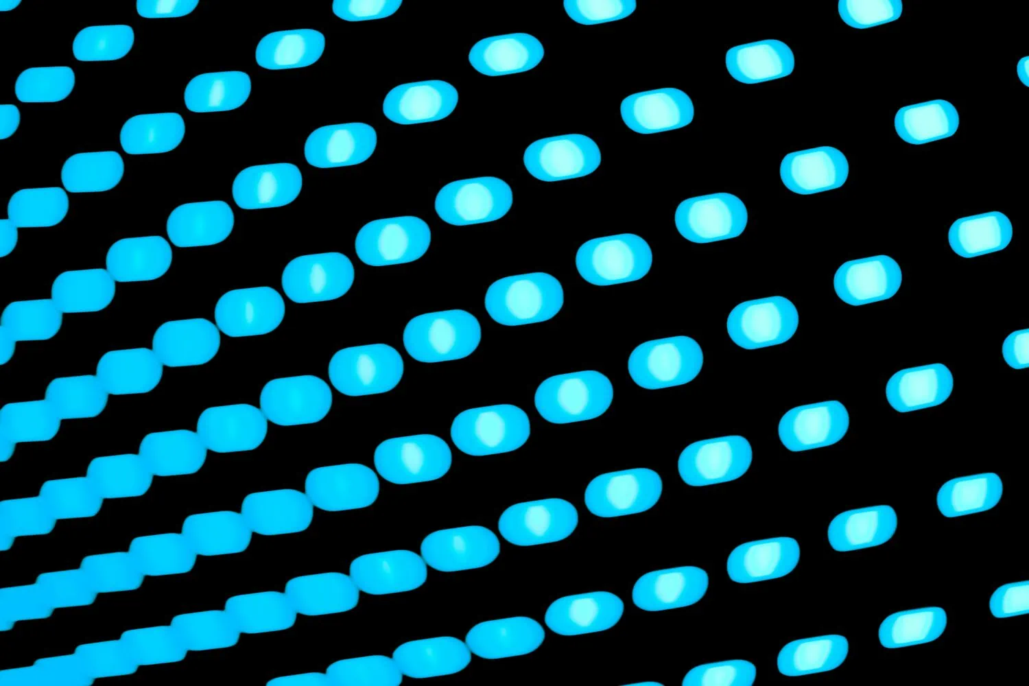 A close-up image of multiple rows of bright blue LED dots arranged diagonally against a black background, offering visual insights as striking as the shifting interest rates in 2021.