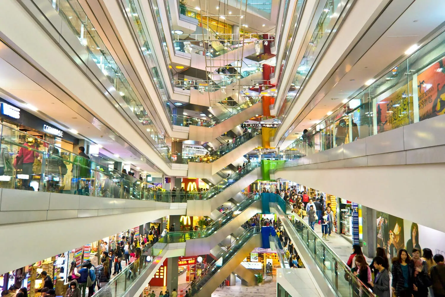 A bustling multi-level shopping mall, invigorated by recent China stimulus efforts, boasts numerous escalators and eager shoppers.