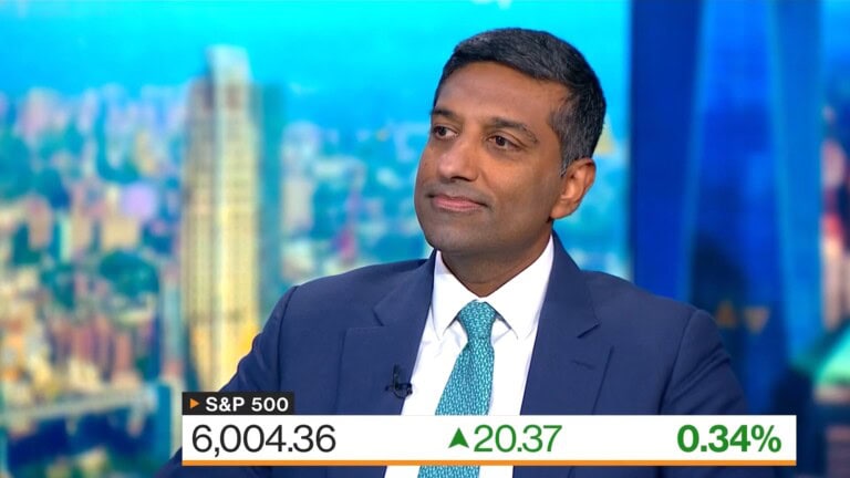 Arjun Raghavan, dressed in a sharp suit, sits confidently in a news studio. The screen behind him displays S&P 500 data: 6,004.36, up 20.37 points or 0.34%.